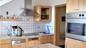 Eine Küche mit Holzausstattung, einem Edelstahlbackofen und einer gefliesten Spritzschutzwand.