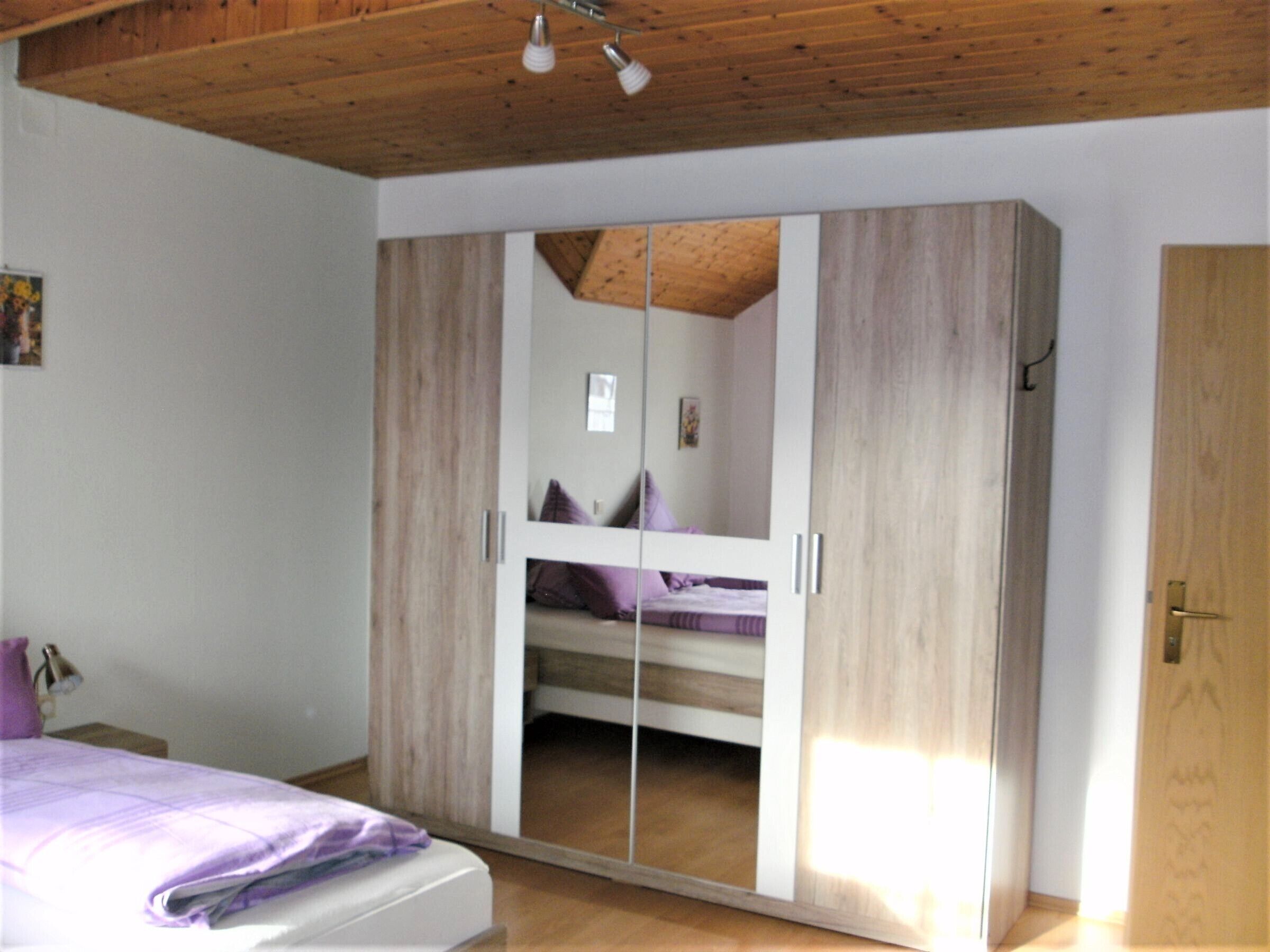 Une chambre avec un plafond en bois, un lit superposé et une armoire avec un miroir.