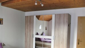 Ein Schlafzimmer mit Holzboden, einem Etagenbett und einem Kleiderschrank mit Spiegel.