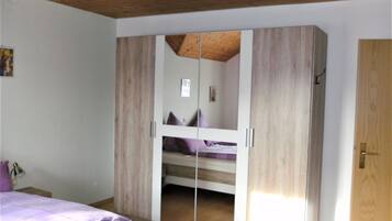 Une chambre avec un plafond en bois, un lit superposé et une armoire avec un miroir.
