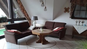 A living room with a brown sofa, a round coffee table, and a lamp. - Apartment 'Heinz Romes' with Shared Terrace, Balcony and Wi-Fi (Wimbach)