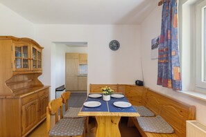A dining area with a wooden table, four chairs, a clock, and a window with curtains. - Apartment 'Gänseblümchen' with Private Terrace, Shared Garden and Wi-Fi (Schmallenberg)