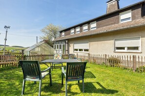 A house with a fenced backyard, a table with chairs, and a garage. - Apartment 'Löwenzahn' with Shared Terrace, Shared Garden and Wi-Fi (Schmallenberg)