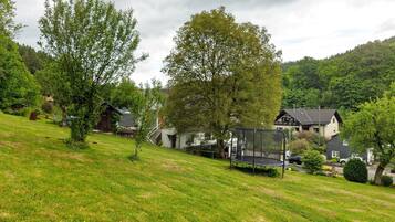 A residential area with houses, a trampoline, and a grassy hill.