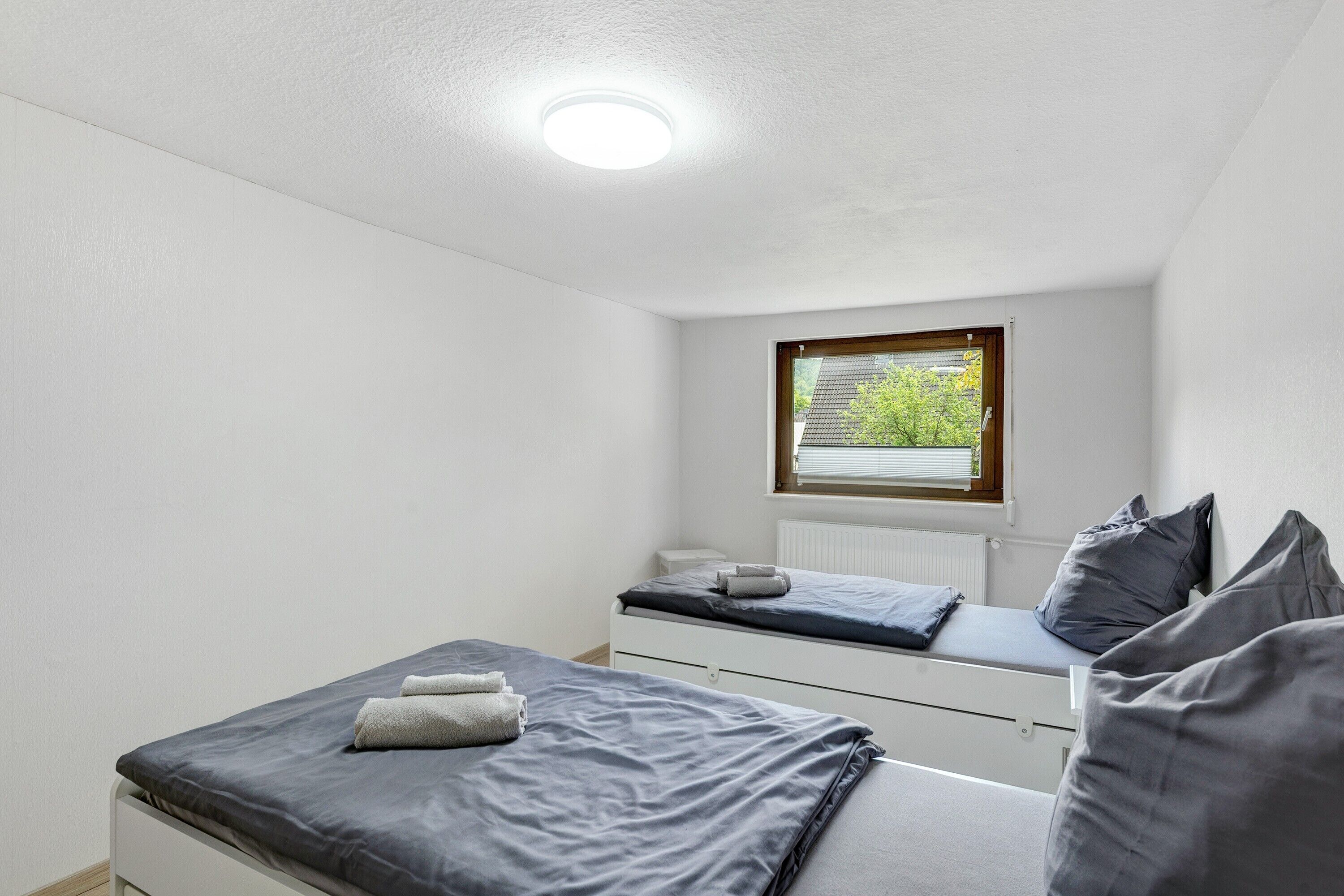 Een slaapkamer met een bed, een raam en een radiator.