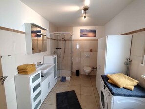 A compact bathroom with a shower, toilet, and washing machine.