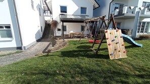 Een woonwijk met een houten speeltoestel, een glijbaan en een trap naar een huis.