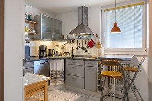 A kitchen with a stove, sink, and a window with blinds.