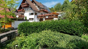 A traditional chalet with a steep roof, wooden balconies with flower boxes, and a well-maintained garden.