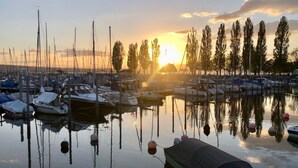 A marina with boats docked, calm water, and a sunset in the background.