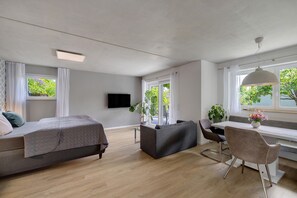 Una camera moderna con un letto, un divano, un tavolo da pranzo e una televisione.