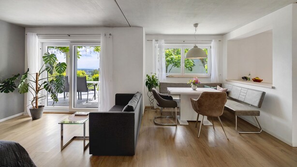 Ein modernes Wohnzimmer mit Essbereich, einer Couch, einem Tisch und einer Bank.