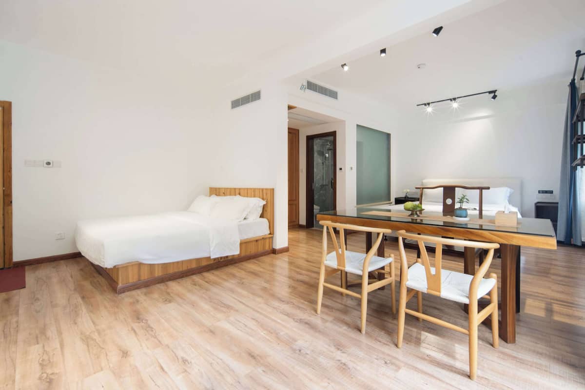 A modern bedroom with a wooden bed, a glass dining table, and two wooden chairs.