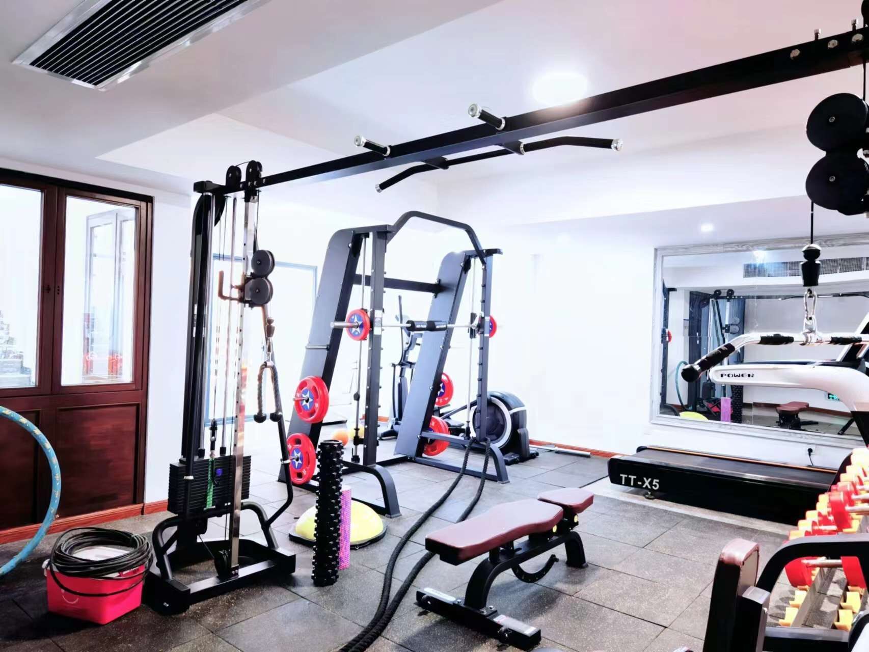 Ett gym med utrustning för styrketräning, en bänk och ett löpband.