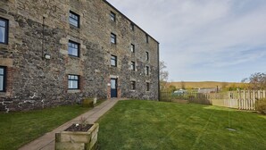 A stone building with a paved entrance and a grassy yard. - Host Stay The Maltings (Belford)