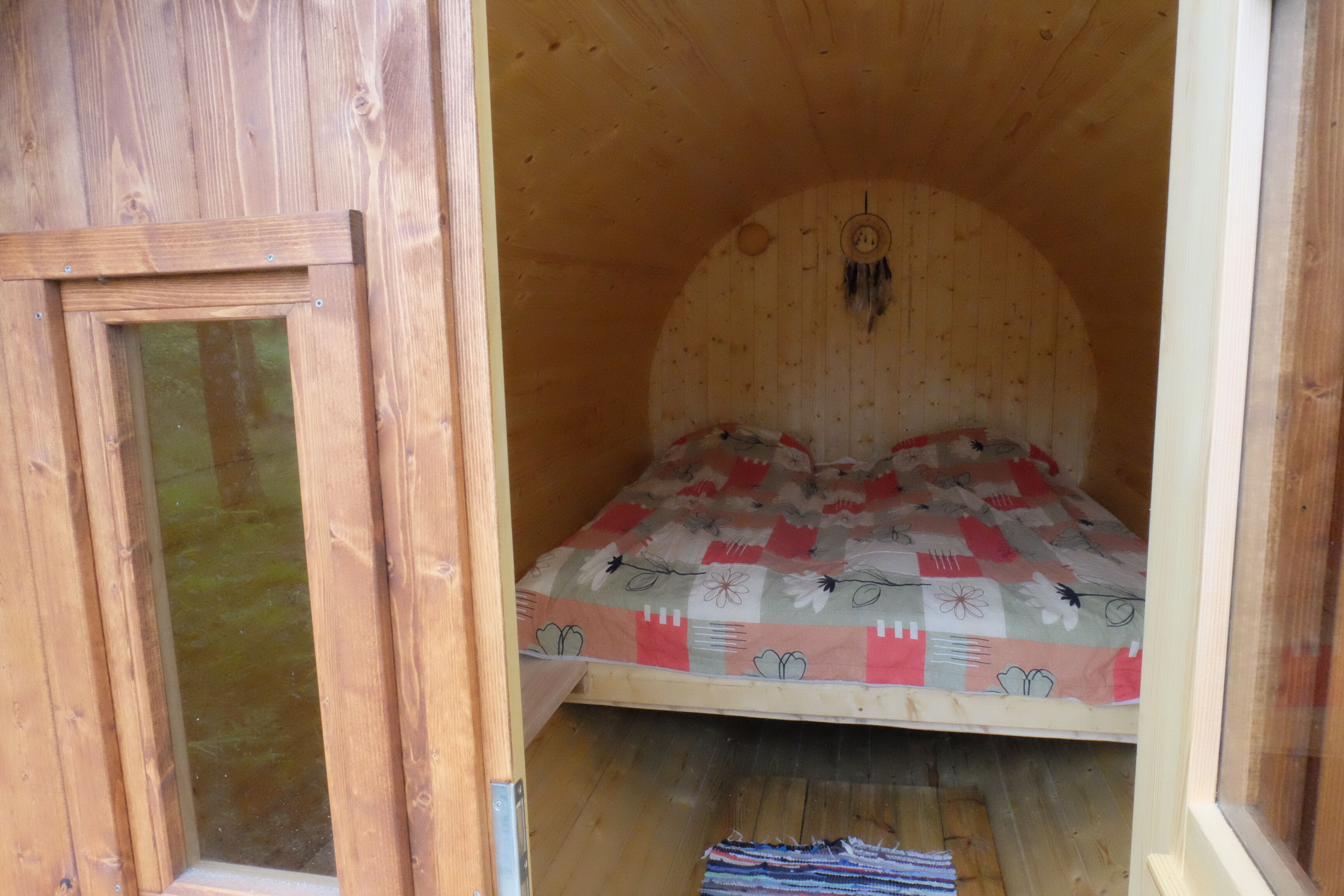 A wooden room with a bed, a window, and a door.