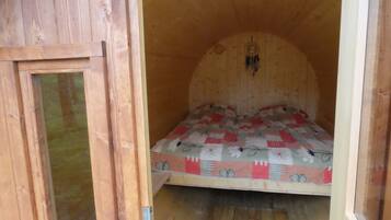 A wooden room with a bed, a window, and a door.
