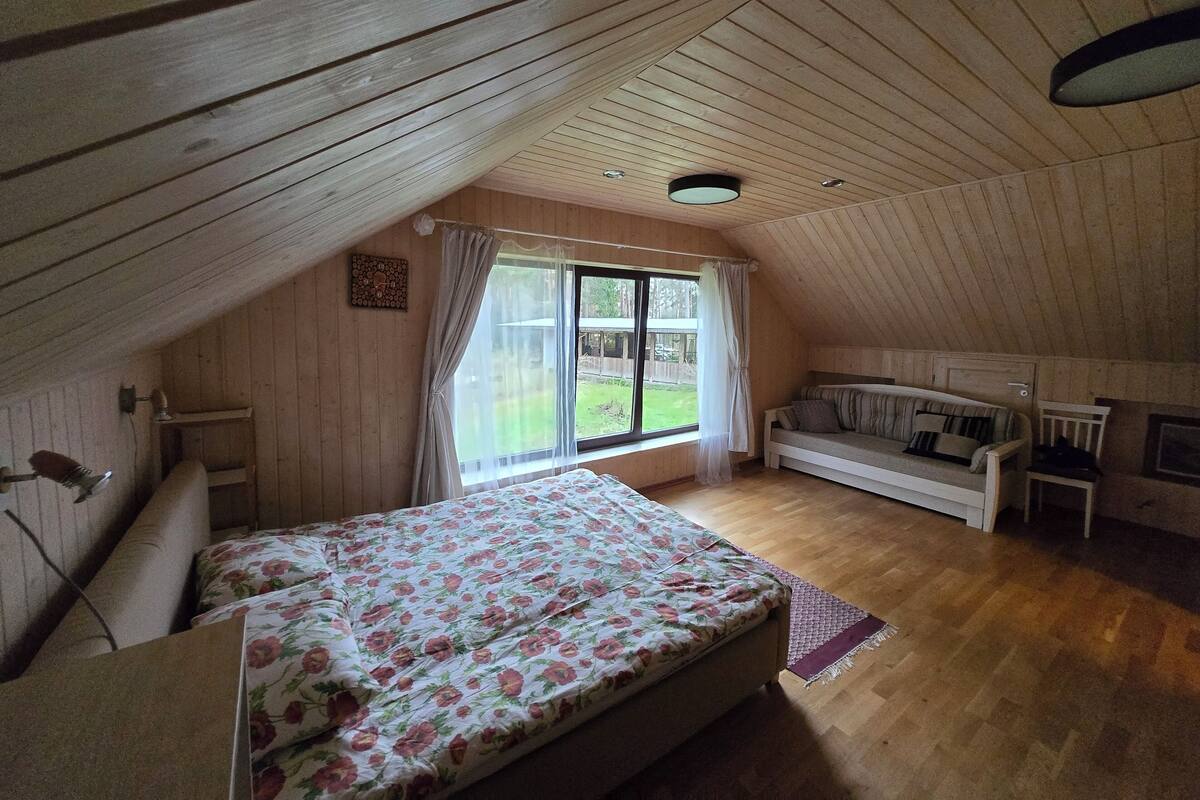 Un dormitorio acogedor en el ático con cama, sofá y ventana con vistas a un jardín.