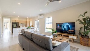 Un salon moderne avec un canapé gris, un téléviseur à écran plat et un ventilateur de plafond.