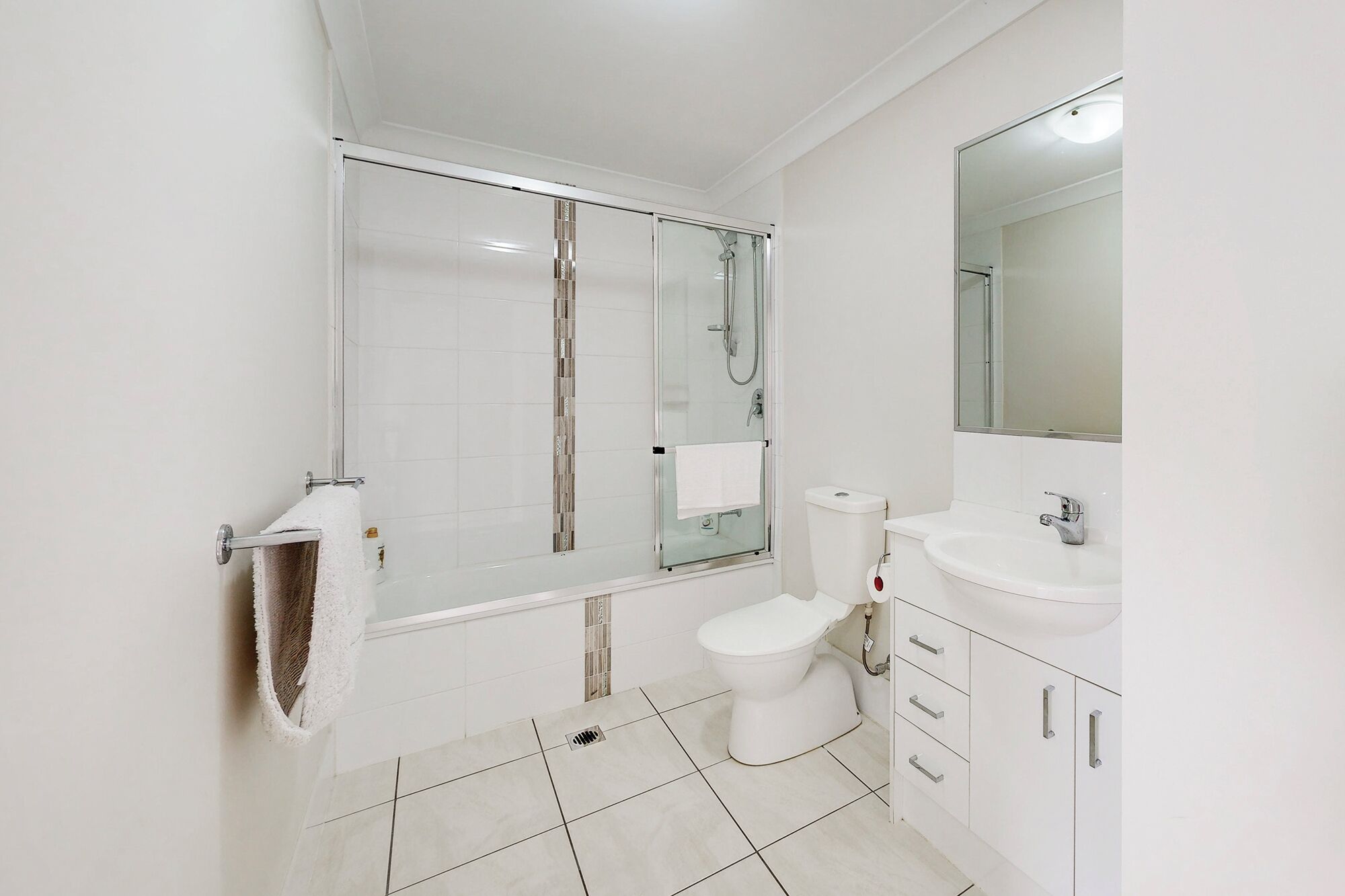 Ein modernes Badezimmer mit einer Duschkabine, einer Toilette und einem Waschbecken mit Spiegel.
