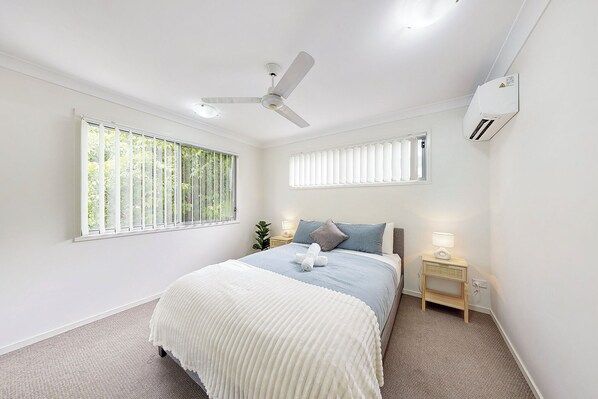 A bedroom with a bed, two bedside tables, a ceiling fan, and a window with blinds. - Homely &  Welcoming in Mango Hill (Moreton Bay City)