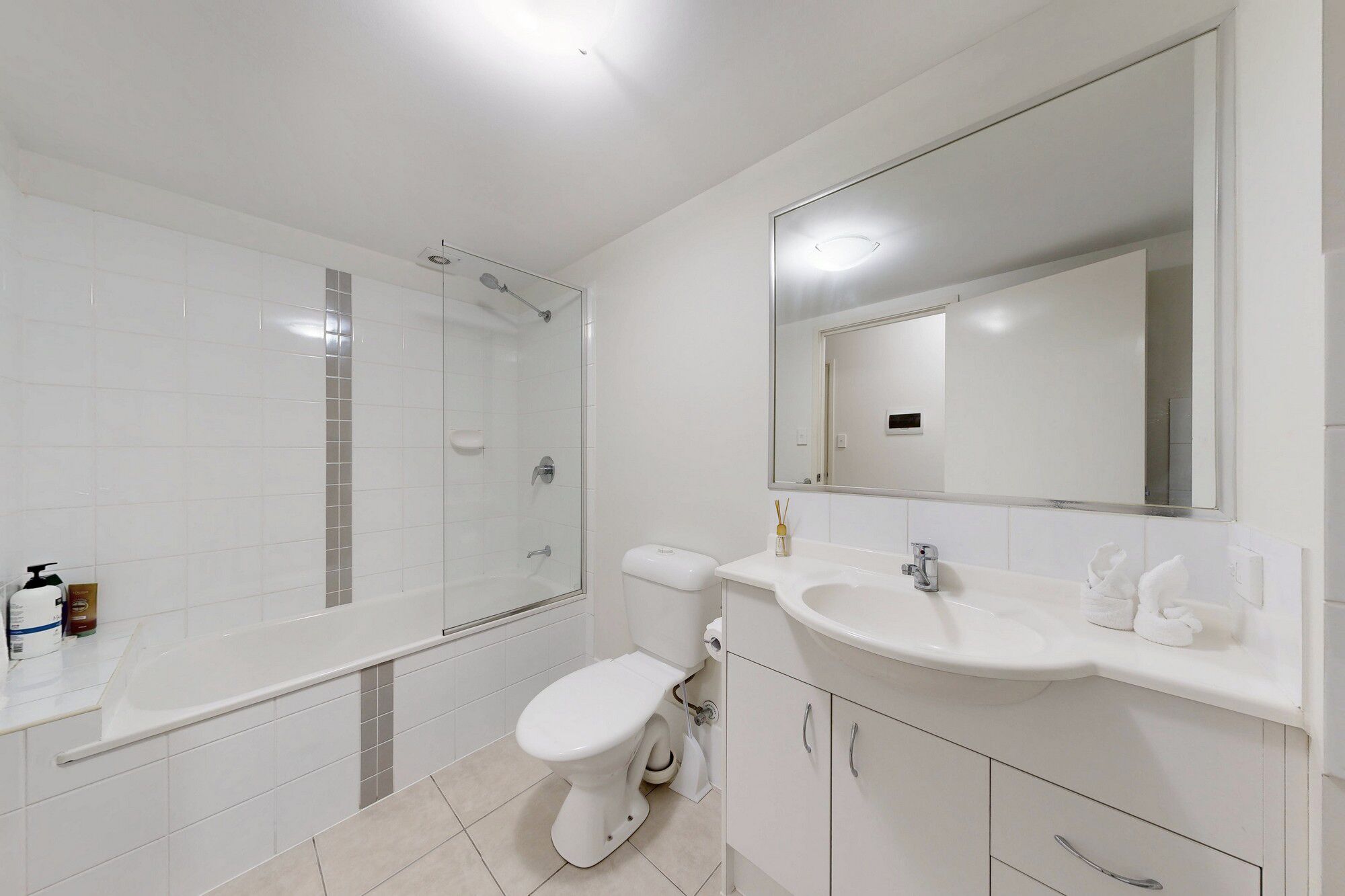 A modern bathroom with a shower, toilet, sink, and mirror.