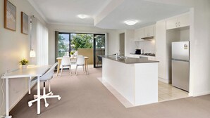 A modern kitchen with a central island, white cabinetry, and a built-in stove.