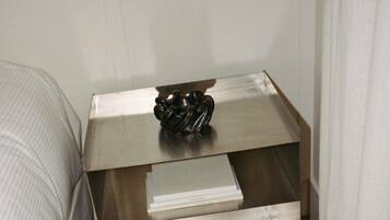 A small, modern room with a bed, a bedside table with a lamp, and a wall socket.