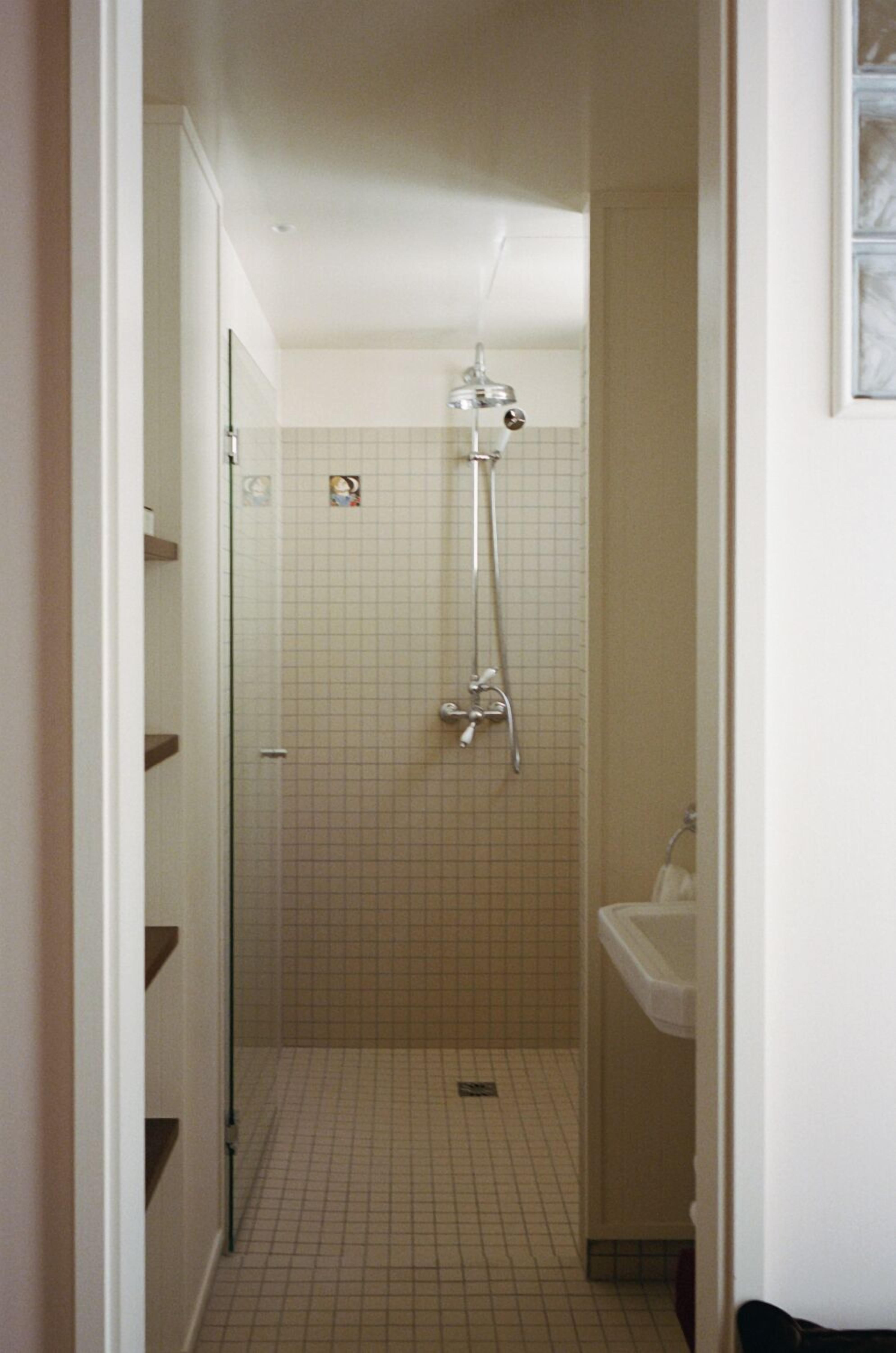 Une petite salle de bain avec une douche, un lavabo et un sol carrelé.