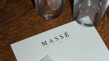A wooden table with a white card labeled "MASSE" and two small packets labeled "PLA PLAQ".