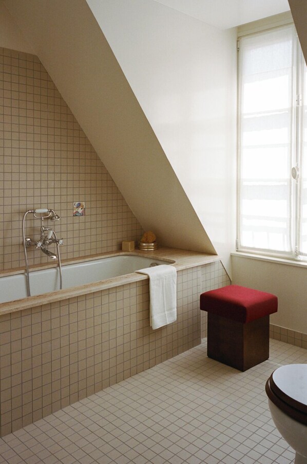 Une salle de bain avec une baignoire, une fenêtre et un banc rouge.