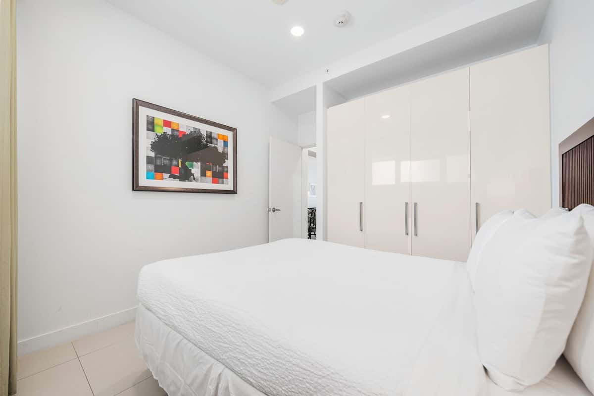 A bedroom with a bed, white wardrobe, and a framed picture on the wall.