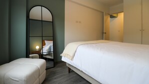 A bedroom with a bed, a bench, a wardrobe, and a mirror. - w* | Warm 1BR in Historic Cusco w/ Balcony (Cusco)