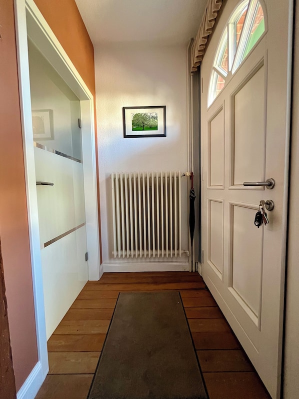 A hallway with a radiator, a framed picture on the wall, and a door with a key in the lock.