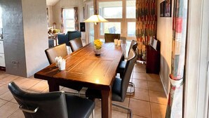 Un comedor con una mesa de madera, sillas y una lámpara colgante.