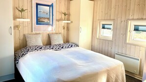 A bedroom with a bed, a window, a radiator, and a wall-mounted picture. - Lakolk - On the beach - Up to 8 people (Rømø)