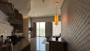 Experience the city from your spacious room with a large window offering a view of the cityscape, a sleek kitchen, and a cozy seating area.