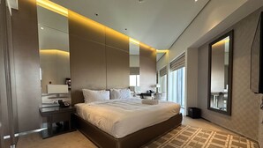 Ein modernes Hotelzimmer mit einem großen Bett, Nachttischen, einem Spiegel und Blick auf die Stadt.