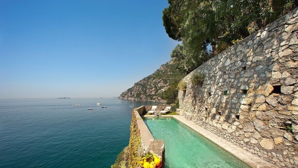 A stone pool with a view of the sea, a wooden deck, and a stone wall. - Casa La Riva with shared pool - My Rental Homes (Positano)
