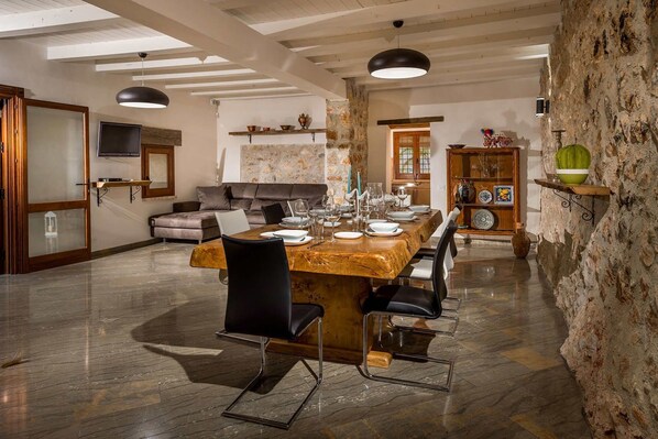 Un espace repas avec une table en marbre, des chaises noires et un mur en pierre.