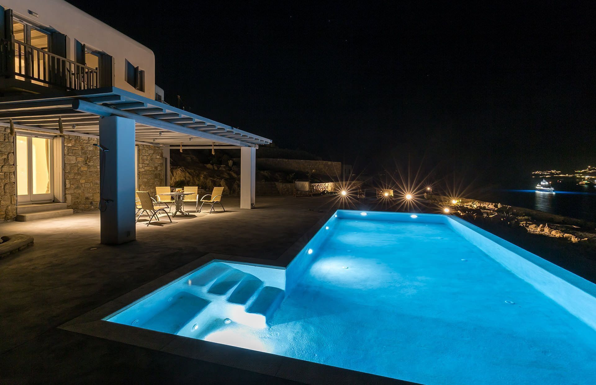A modern outdoor pool area with a stone wall and a covered seating area.