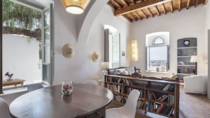 A cozy reading nook with a wooden table, white chairs, and a bookshelf filled with books.