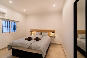 A bedroom with a bed, bedside lamps, a window with bars, and a mirror. - Sunsands Benalmádena 1 (Benalmádena)