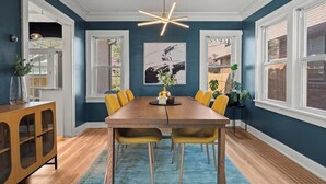 A dining room with a long wooden table, yellow chairs, and a modern pendant light. - Casa Brookside - Brookside + Walkable + Firepit (Kansas City)