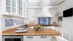 A kitchen with white cabinetry, a wooden countertop, and a blue and white tiled backsplash. - Villa Ieranto 6 with private pool, My Rental Homes (Massa Lubrense)