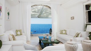 A spacious living room with a view of the sea, white furniture, and a bookshelf. - Villa Ieranto 6 with private pool, My Rental Homes (Massa Lubrense)