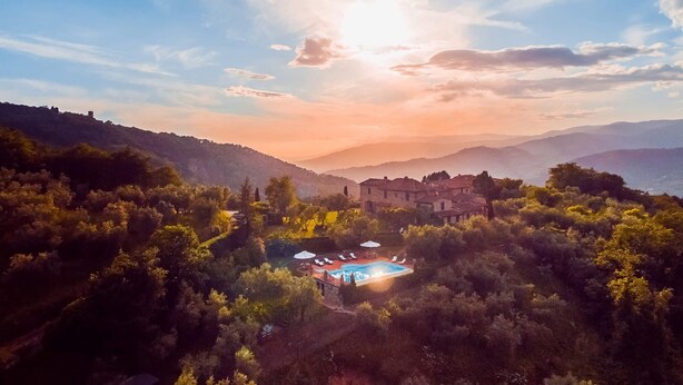Eine Villa mit Swimmingpool, umgeben von dichtem Wald, mit Blick auf eine gebirgige Landschaft.