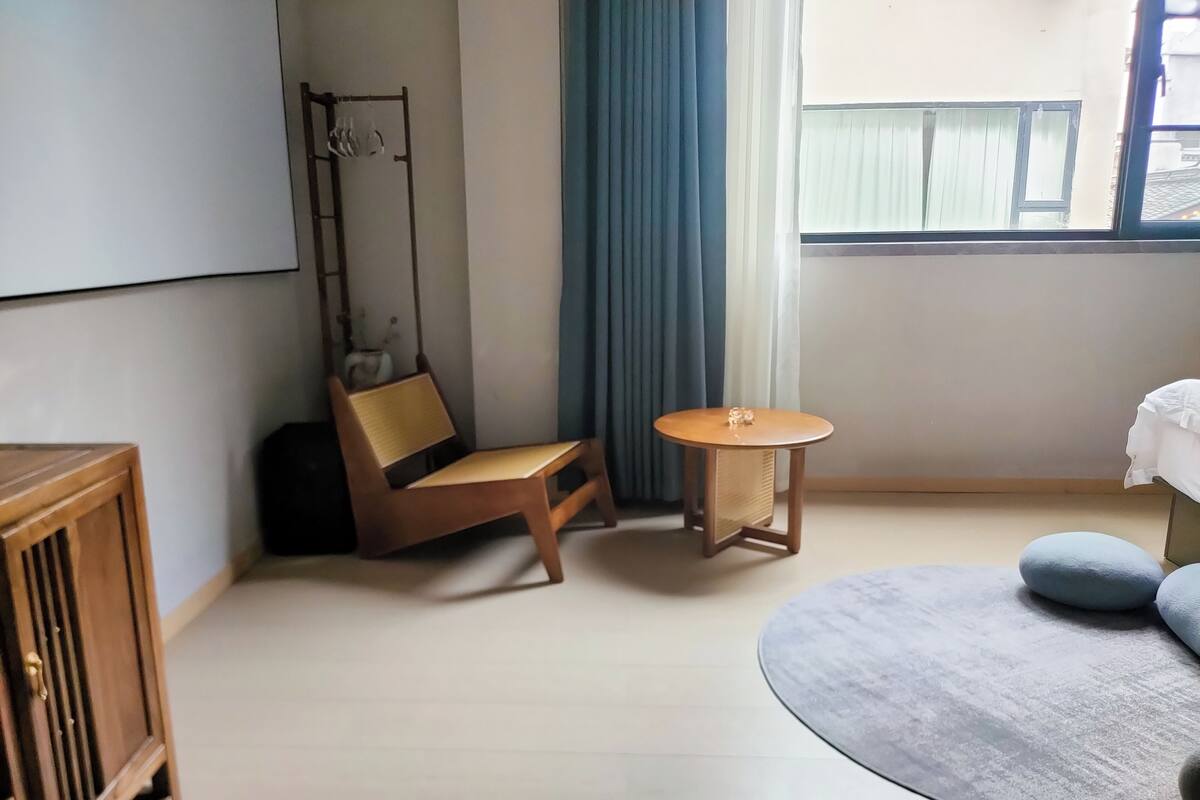 Une pièce comprenant une chaise en bois, une petite table ronde, un canapé et un meuble.