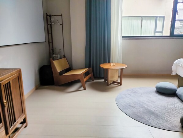 A room with a wooden chair, a small round table, a sofa, and a cabinet. - Homie Inn (Changsha)