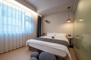 A modern hotel room with a large bed, a bedside table, a nightstand, and a large window with sheer curtains. - Homie Inn (Changsha)